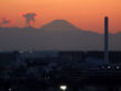 冬の夕日を背景にした富士山を都内より眺める